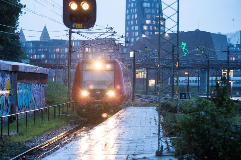 Et S-tog kører til en station i regnvejr