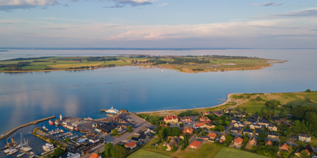 Luftfoto af kystlinje med spredt bebyggelse og grønne områder