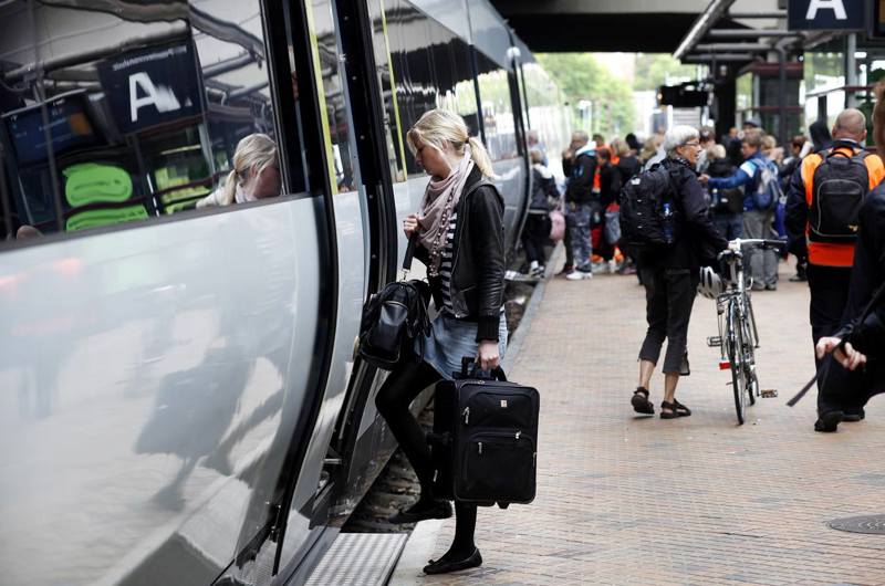 Passager stiger ind i et IC 4-tog på en station med andre passagerer i baggrunden