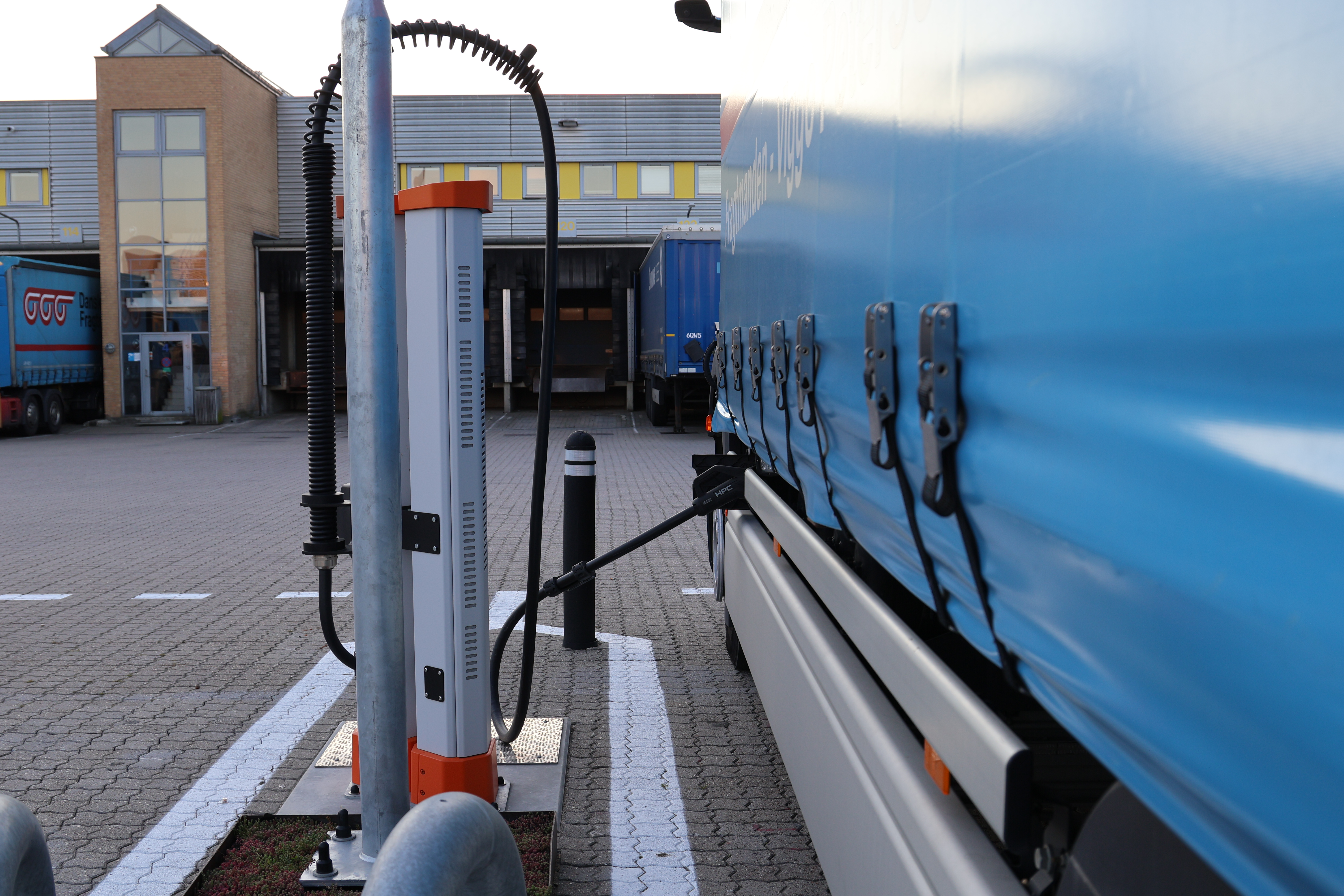 Lastbil, der holder ved en ladestander og lader